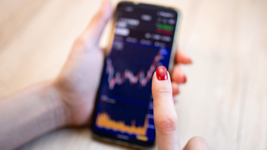 スマートフォンで投資をする女性の手